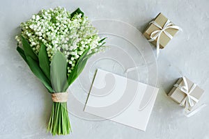 Greeting card mockup. Bouquet of lilies of the valley, postcard, gift boxes on a light blue background