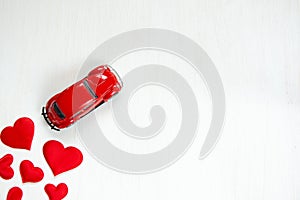 Greeting card with red hearts and a toy car on a white background. Valentine`s day holiday concept. Flat lay, copy space