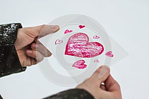 Greeting card with a red painted heart in the hands, a declaration of love on Valentine`s Day