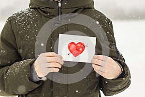 Greeting card with a red painted heart in the hands, a declaration of love on Valentine`s Day