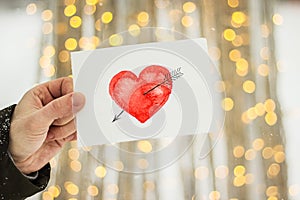 Greeting card with a red painted heart in the hands, a declaration of love on Valentine`s Day