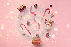 Greeting card with snow, lights bokeh for New year party. Christmas gifts, decorative elements and ornaments on pink background.