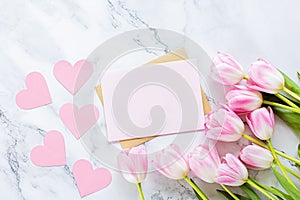 Greeting card for spring holiday, pink tulip flowers lying on white marble background with copy space. Flat lay top