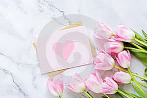 Greeting card for spring holiday, pink tulip flowers lying on white marble background with copy space. Flat lay top