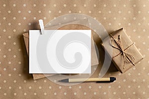 Greeting card stationary mockup with envelope, pen and gift box on craft paper background