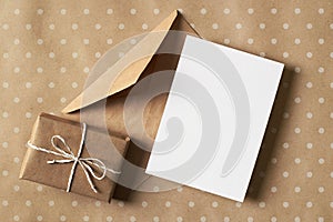 Greeting card stationary mockup with gift box and envelope on craft paper background