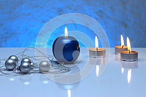 Greeting card template made of blue and tea candles, silver christmas balls, silver string of beads and blue ribbon in front