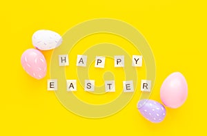 Greeting card with text HAPPY EASTER. Multicolored easter eggs and paper rabbits on yellow background