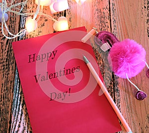 Greeting card with text Happy Valentines Day  and  Pen with toy pink flamingo . In dark settings.  Concept of love and romance