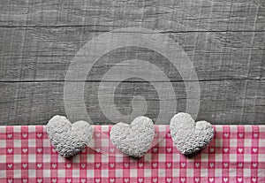Greeting card: three white and pink checked hearts on wooden grey shabby chic background.
