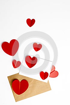 Greeting card for Valentine`s Day. Envelopes on a white background and red plastic hearts