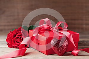 Greeting card for Valentines or Mother day. Gift box, red heart and rose flower on wooden rustic table.