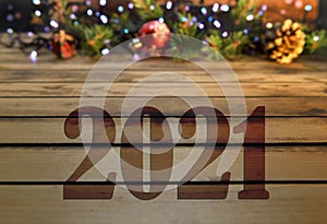 Greeting card 2021 on wooden table and christmas oranment in lights background