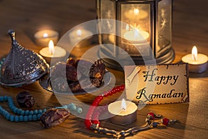 Greeting card writing Happy Ramadan with dates, rosary, candles on wooden table