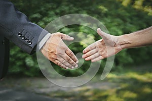 Greeting handshake close-up on the background of the park. Meeting friends in nature. businessman and employee. boss and