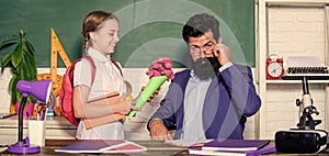 Greetings for school pedagogue. Girl adorable pupil with backpack giving bouquet flowers teacher. Knowledge day