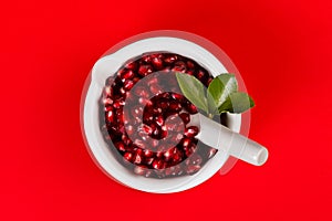 Grenadine seeds in a mortar on red photo