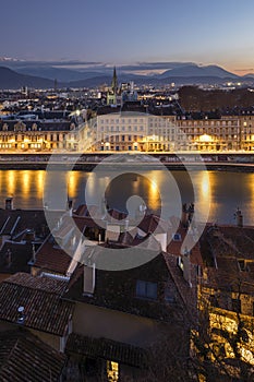 Grenoble, France, January 2019 : City at sunset with isere river and the mountains in the background