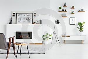 Grey armchair next to table in scandi living room interior with