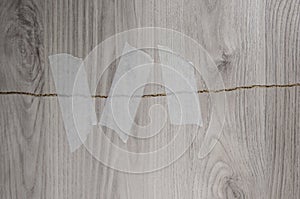 Grey background of broken plywood board with texture sealed with tape