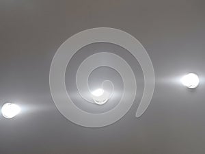 Grey background with three recessed light bulbs with mostly just lights blended in showing