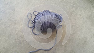 Grey ball of threads wool yarn for knitting on grey floor background