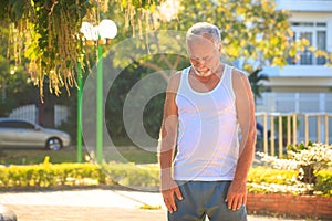 Grey Bearded Old Man in Vest Stretches Fingers in Park