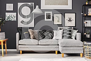 Grey and black pillows on comfortable corner sofa in scandinavian living room