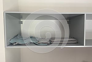 Grey and blue blankets in open wall shelf