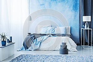 Grey boxes next to bed with blue bedding in bedroom interior wit