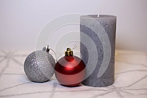 Grey Candle and Christmas Ornaments on a White and Silver Blanket Surface
