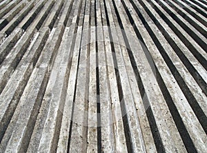 Grey cast concrete with vertical ribbed texture with a converging view in sunlight and shadow