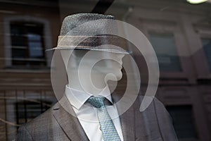 Grey classic suit for men on manequin with hat in a fashion store showroom