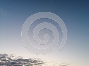 Grey clouds outlined by sunset in a Blue-ish sky