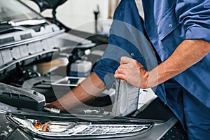 Grey colored oil can in hands. Auto mechanic working in garage. Repair service