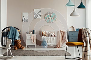 Grey crib with blue blanket in the corner of classy baby bedroom