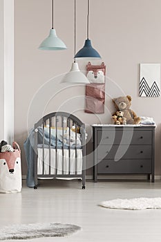 Grey crib in fashionable scandinavian baby bedroom interior