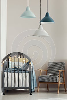 Grey crib in fashionable scandinavian baby bedroom interior