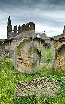 Grey cumulonimbus clouds over eroded gravestones with Whitby Abbey in the background. North Yorkshire.