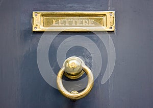 Grey door with a gold doorknocker and mailbox