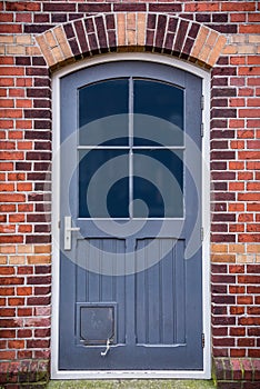 Grey door with windows in a stone brick wall with a cat  flap