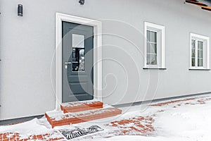 Grey entrance door with glass leading to a private house. Winter, snow