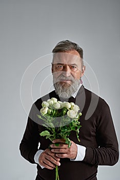 Grey hair serious man with bouquet of white roses