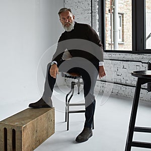 Grey hair serious man posing in spacious flat