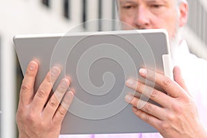Grey-haired bearded man reading on a tablet