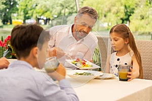 Grey-haired grandfather giving some vegetable salad for his girl