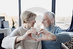 Grey haired man and his wife making heart shape gesture