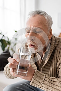 grey haired man with parkinsonism holding