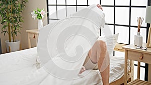 Grey-haired man taking glasses off lying on bed to sleep at bedroom