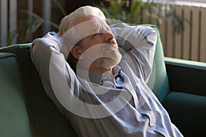 Grey haired senior man sitting leaning on couch recovers strength